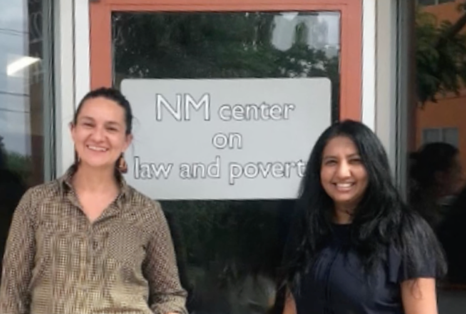 Two women standing in front of a door that says "NM center on law and poverty"